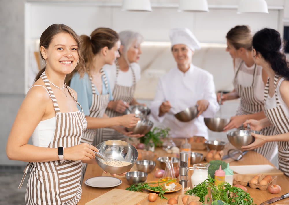 Girl while studying at culinary workshop, cooks appetizing sauce, marinade, dough in bowl.