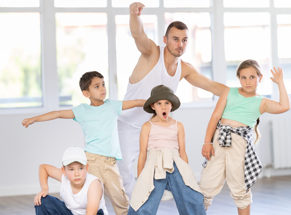 Group of preteen boys and girls hip hop dancers posing in dance studio
