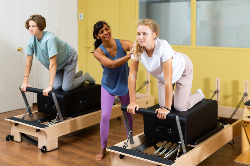 Young boy and girl with pilates trainer in gym