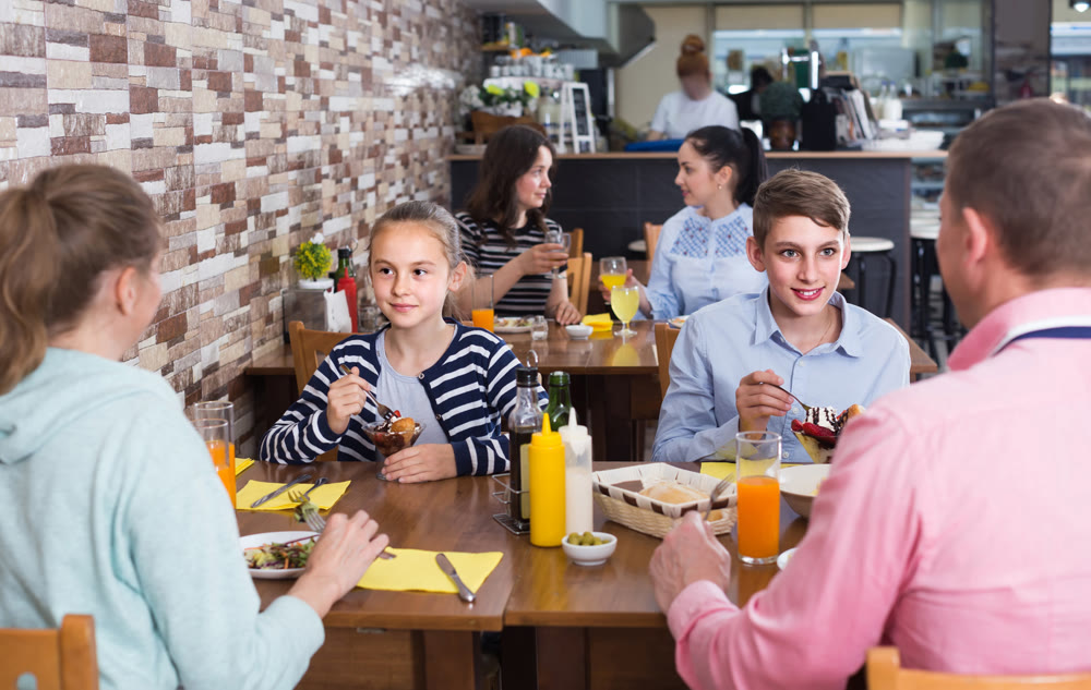 family with teenage children enjoying meal in cafe