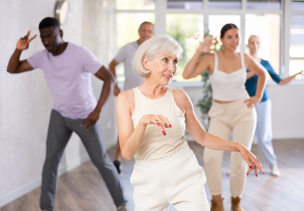 Female instructor teaches senior students of different ages basic movements of contemporary dances