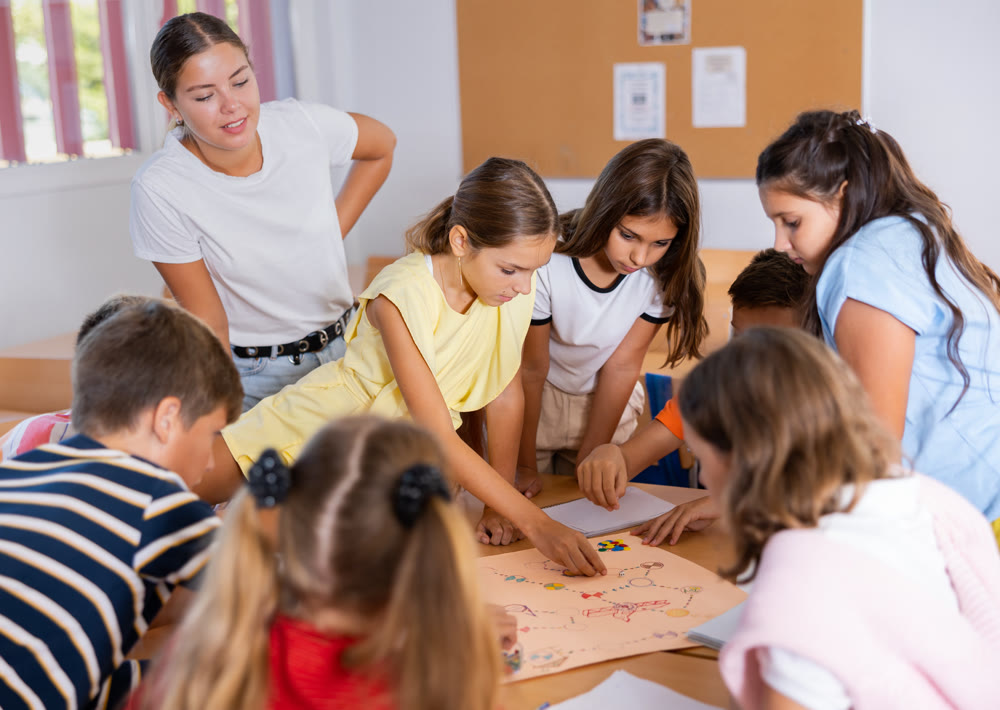 Schoolkids with teacher playing educational tabletop game in classroom