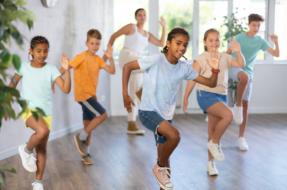 Active preteen children practicing Hip-hop dance with young trainer