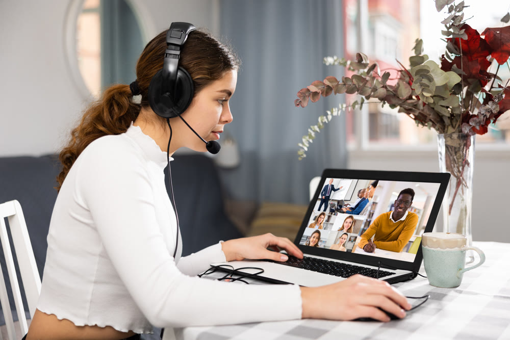 Young woman having video call conversation with co-workers at home