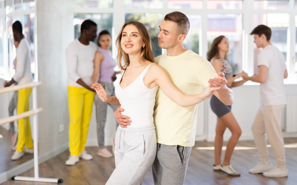 Man and young woman dancing waltz in couple during lesson at studio