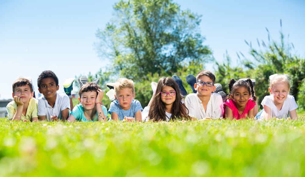 Team of friends children resting on grass together in park