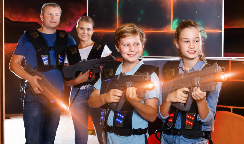 Happy teen brother and sister standing with laser pistols during