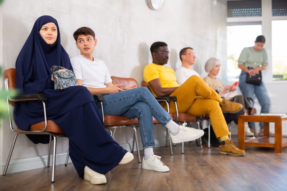 Young arab woman and teen boy waiting in line at reception