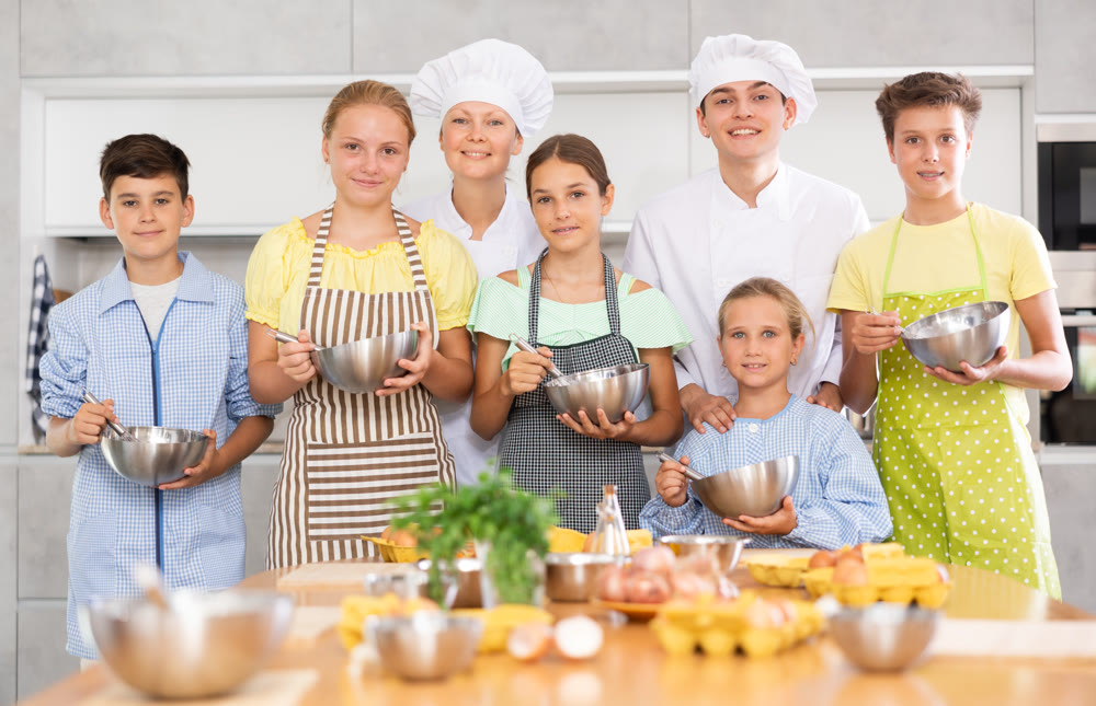 Group portrait of kids together with two chefs at cooking class