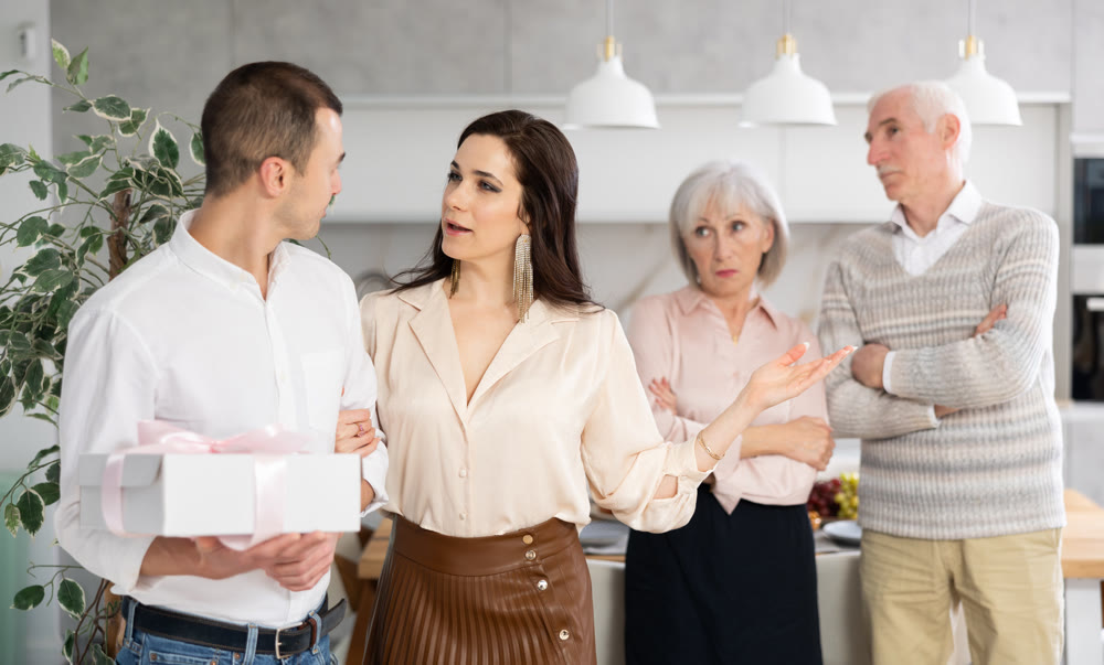 Woman welcoming boyfriend home while senior parents disapproving