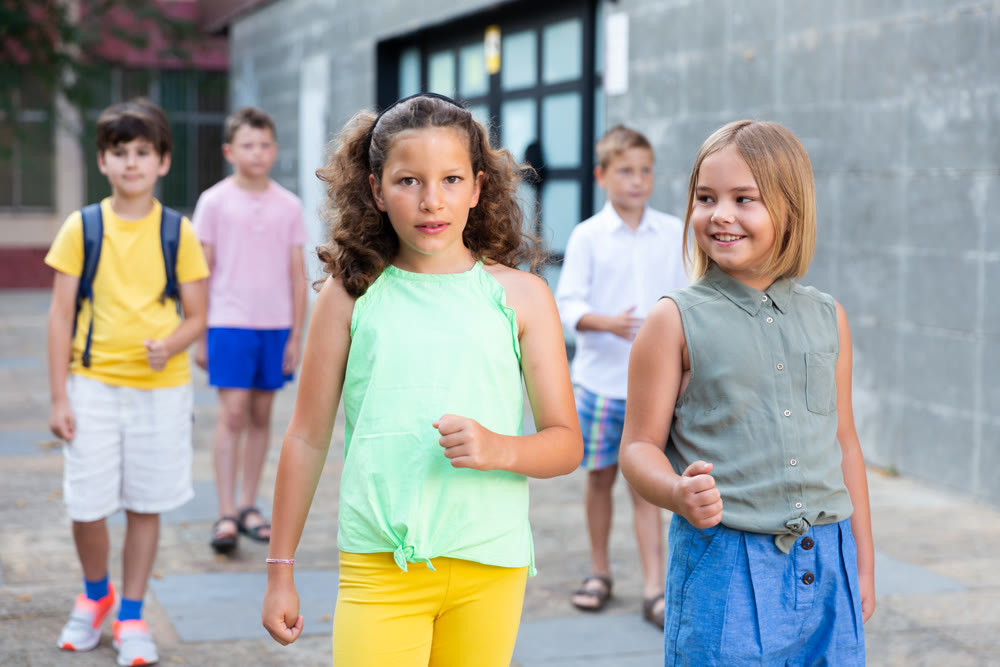 Friendly preteen girls talking during walk along city street