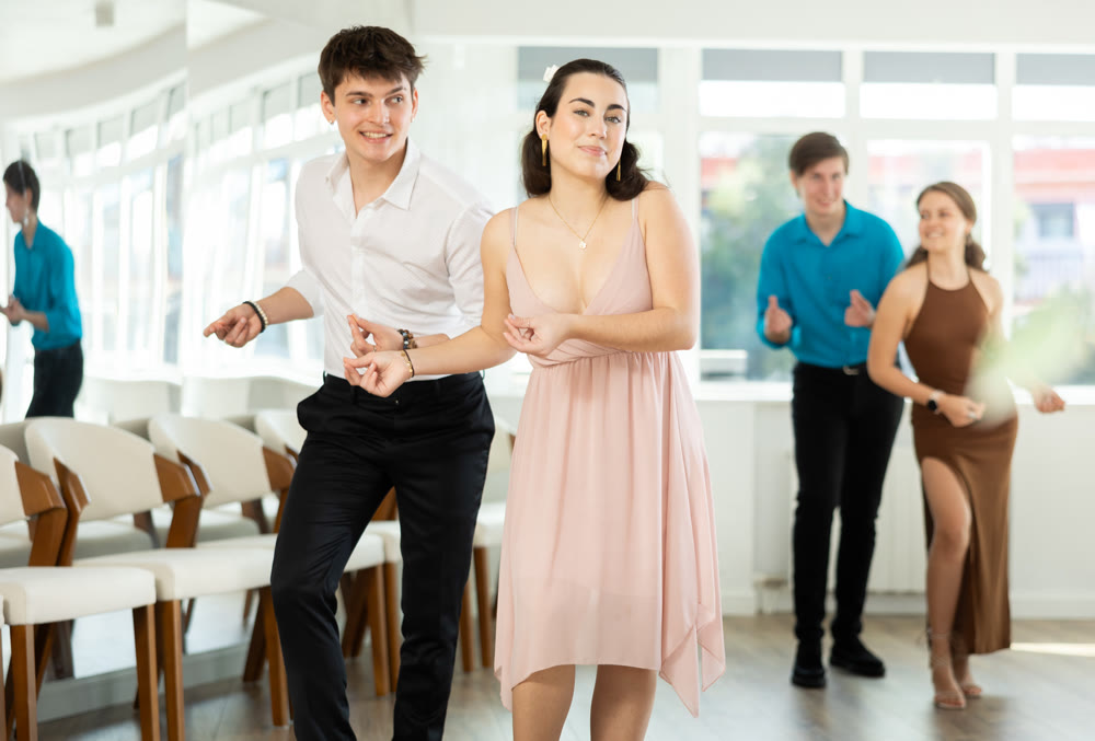 Dance studio where young couples in festive clothes learn to dance swing