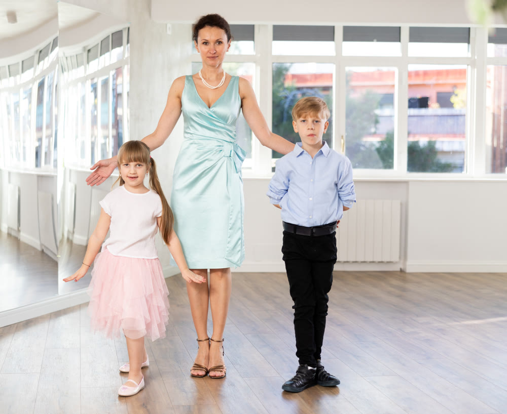 Female choreography teacher stands next to couple of teen boy and girl students