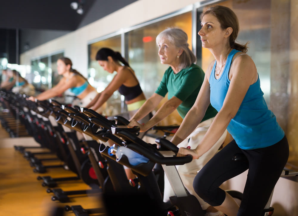 Elderly woman warming up on bike at gym