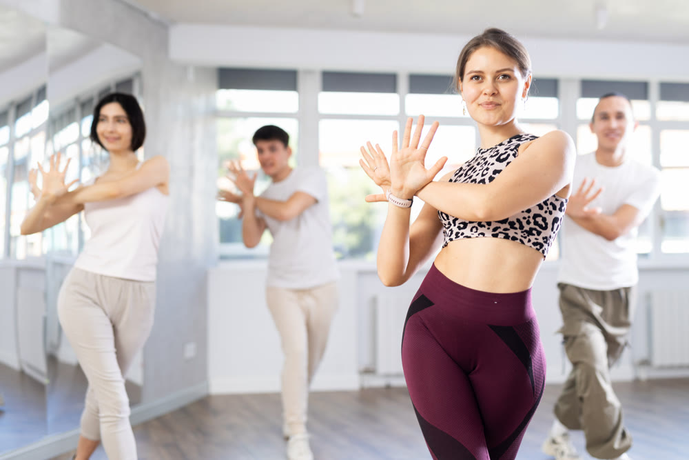 Cheerful young female instructor leading zumba class