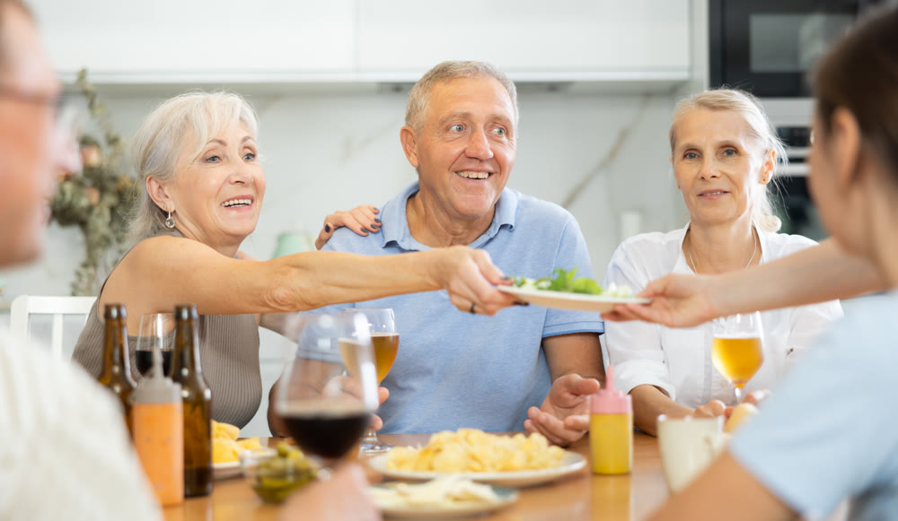 Happy elderly friends spending free time together in kitchen of nursing home - having lunch and chatting