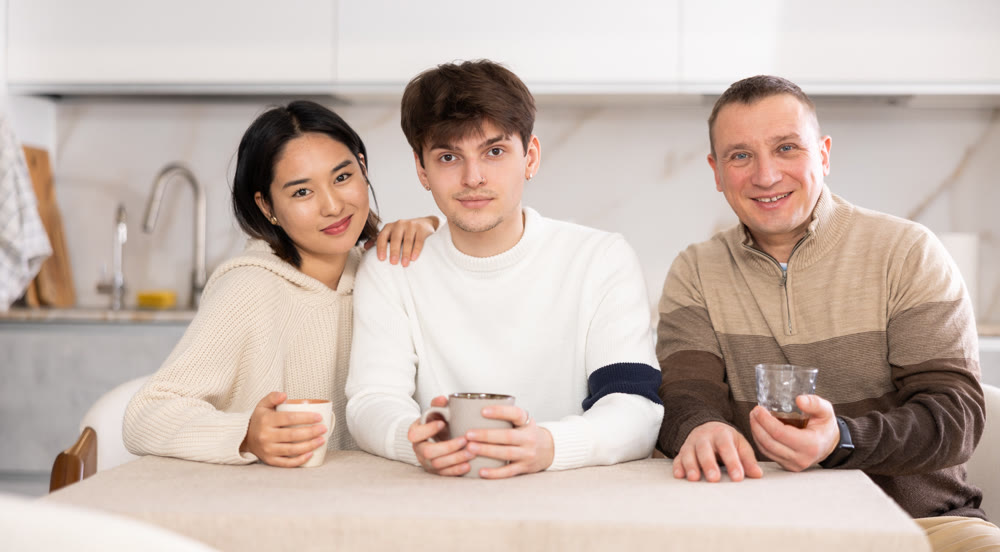 Adult man and couple sitting at table in kitchen