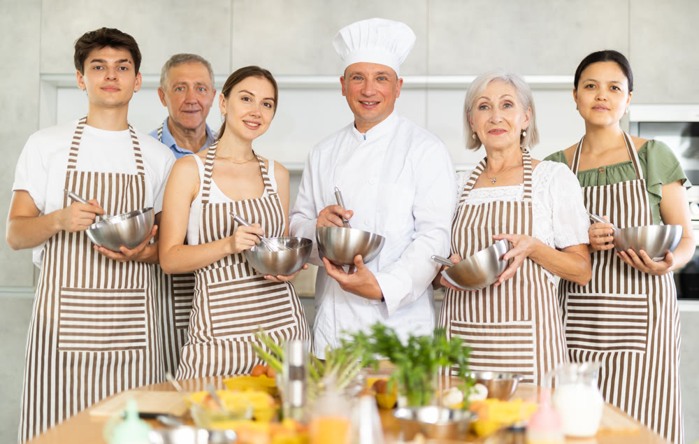 Successful male chef posing with group at cooking course