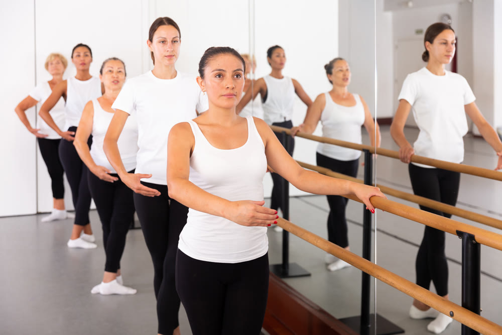 Latino woman training in ballet class with other dancers