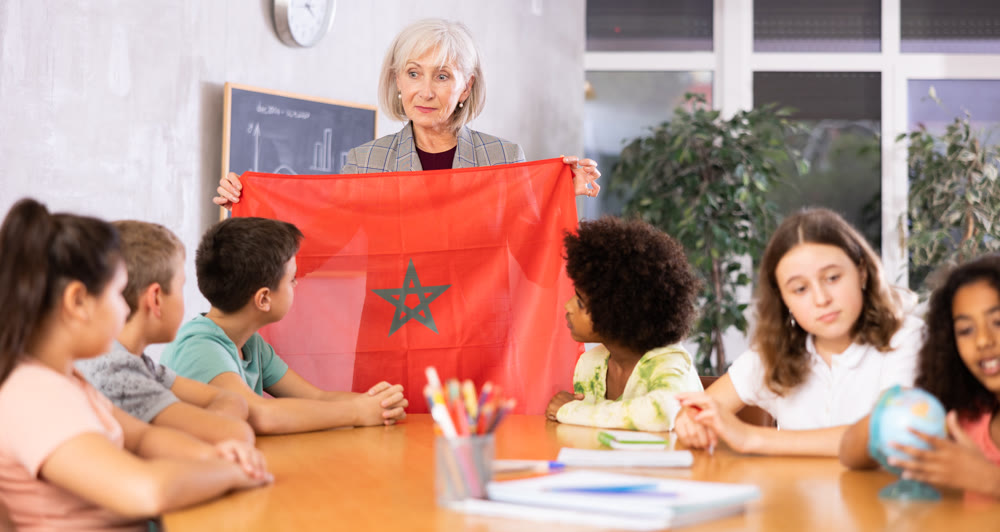 Mature female teacher tells the pupils the history of Marroko