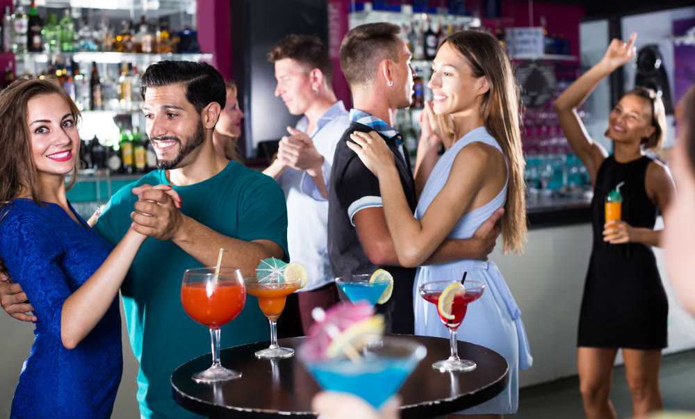 glad women with men are dancing in pairs in the nightclub