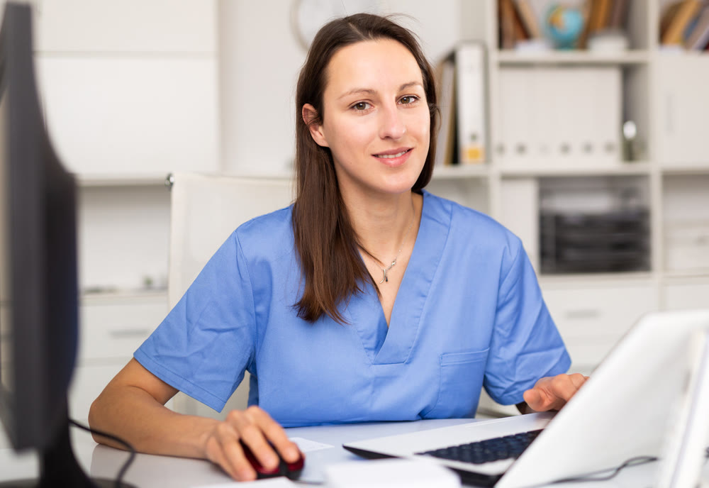 Portrait of female doctor who is working with laptop and documents