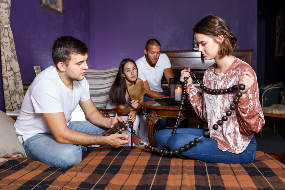 Young adults inspecting wooden rosary in escape room
