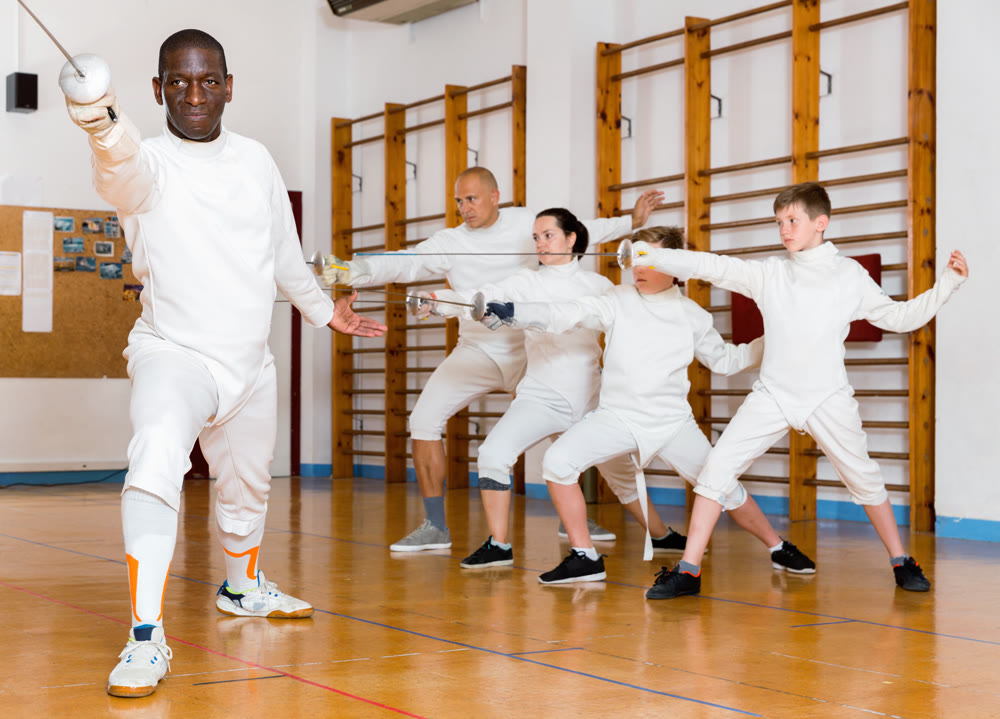 African American fencer practicing effective fencing techniques in training room
