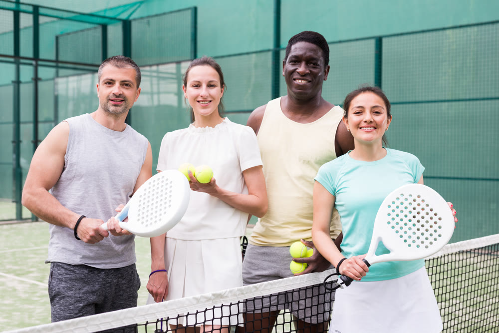 Two happy couples after playing padel on tennis court