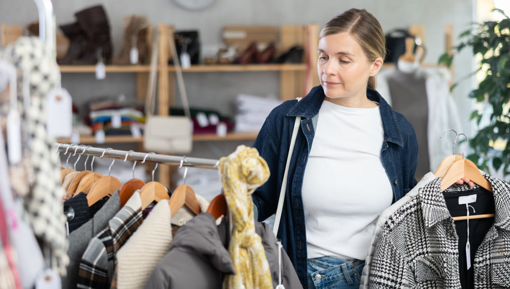 Adult woman chooses coat in clothing store