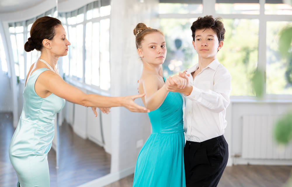 Female dance teacher fine-tuning positions of teenage students during dance class