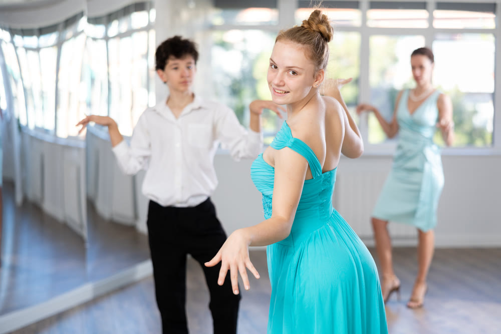 Happy girl an boy dancing foxtrot in choreographic studio