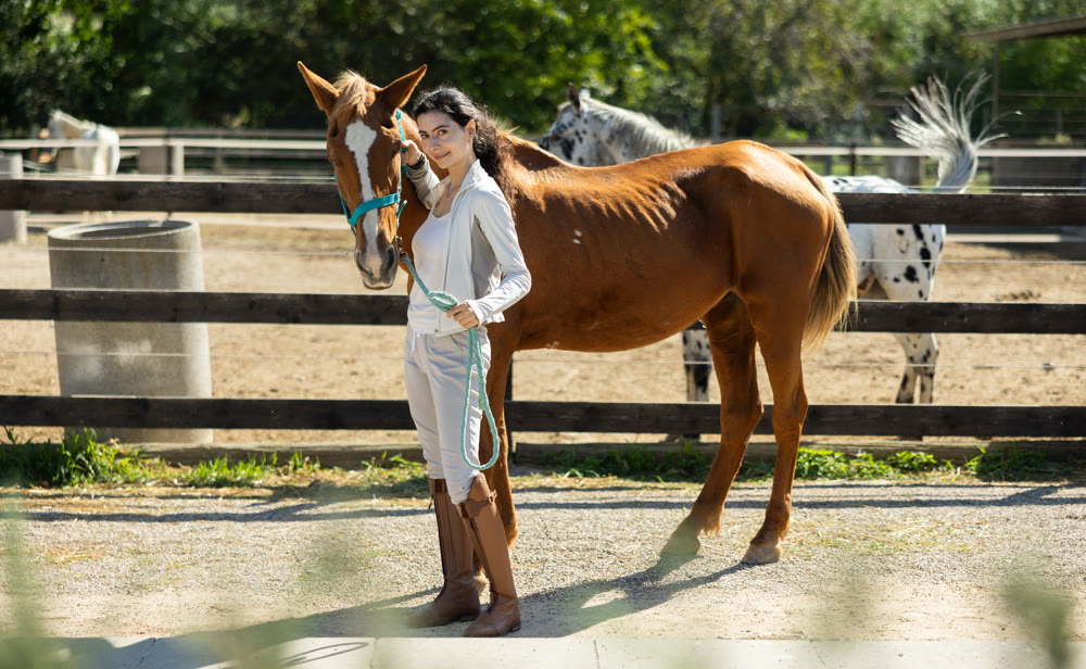 Armenian girl, owner of horse, walks pet outdoor in paddock