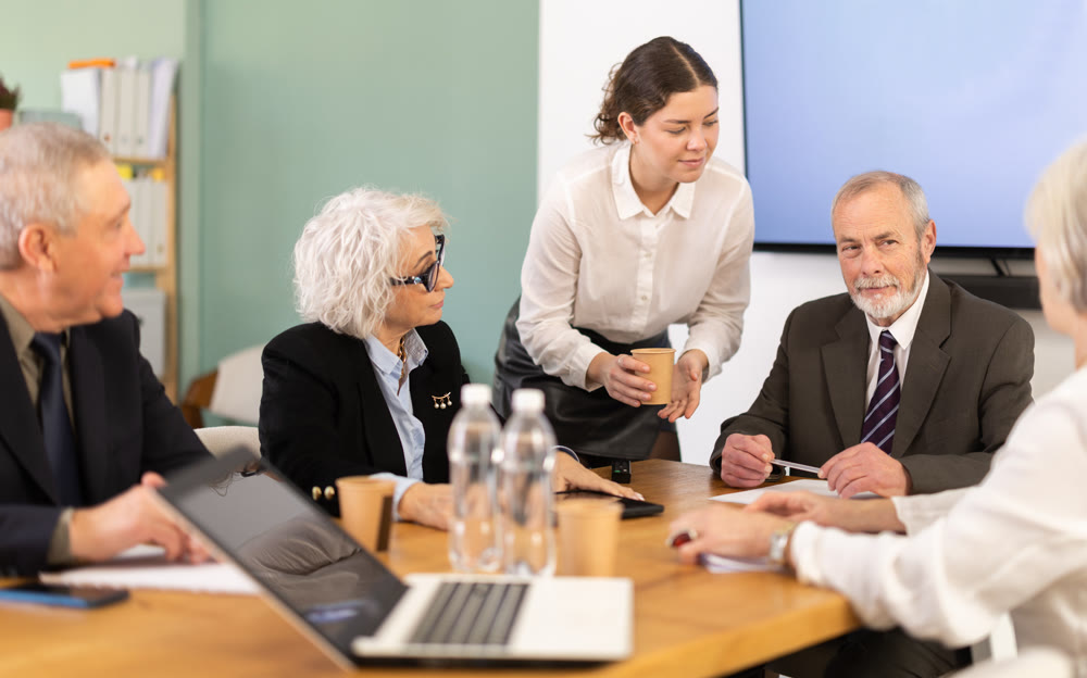 Group of interested business colleagues sitting at table in office, planning work in joint meeting