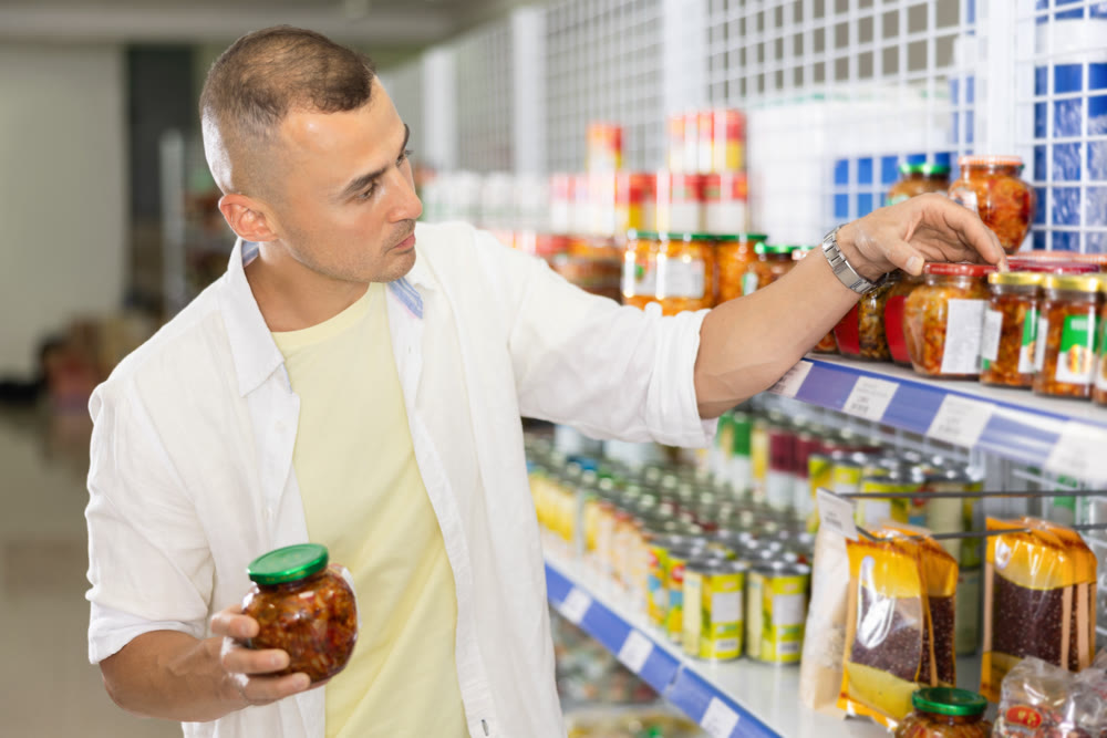 Young man chooses mustard in store