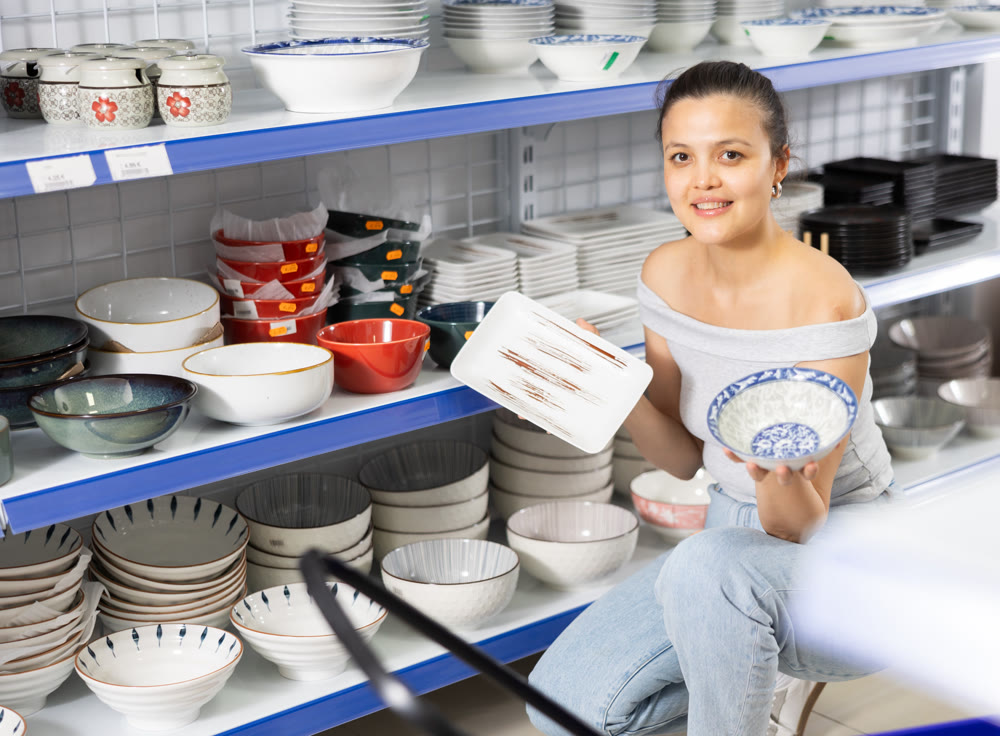 Woman looking for new plates at store of household goods