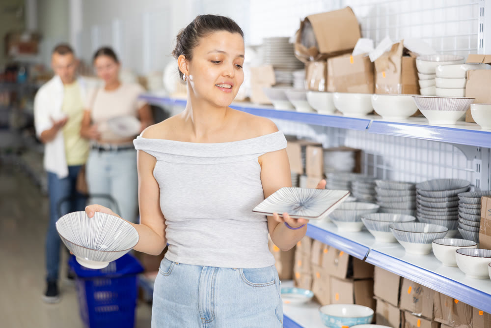 Woman looking for new plates at store of household goods