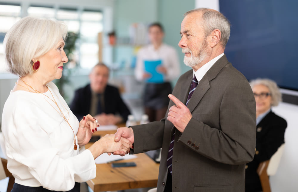 Man and woman shake hands in gratitude after signing a contract at business meeting