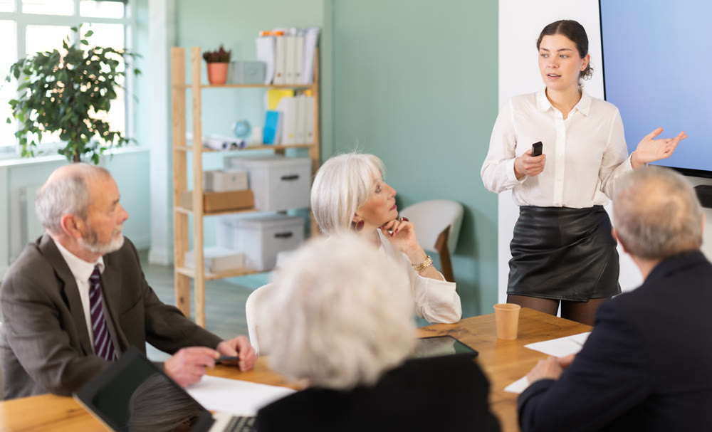 Girl with remote controller tell material, speaks to mature precursors of business group