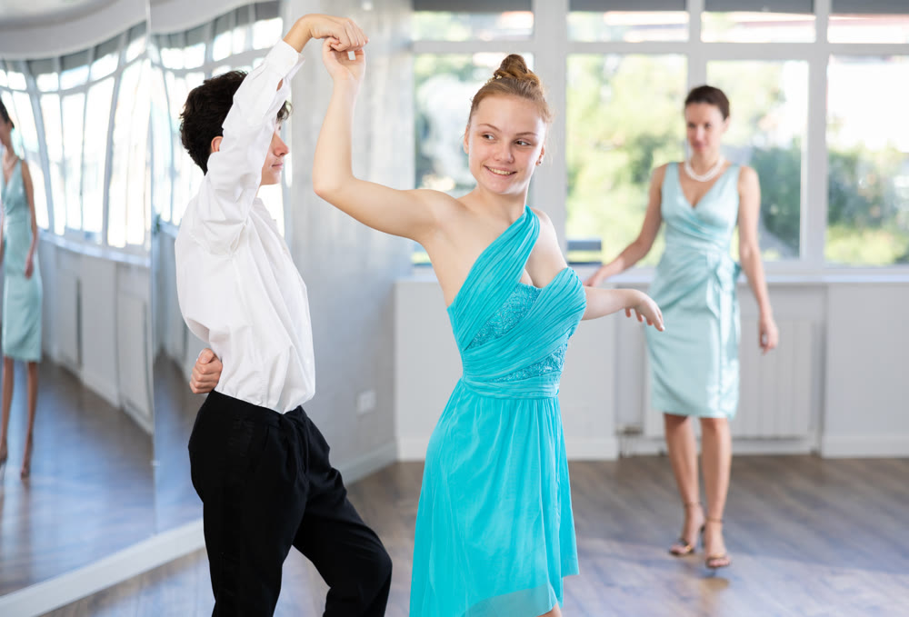Couple of teenagers in evening dresses are learning to dance an polonaise dance