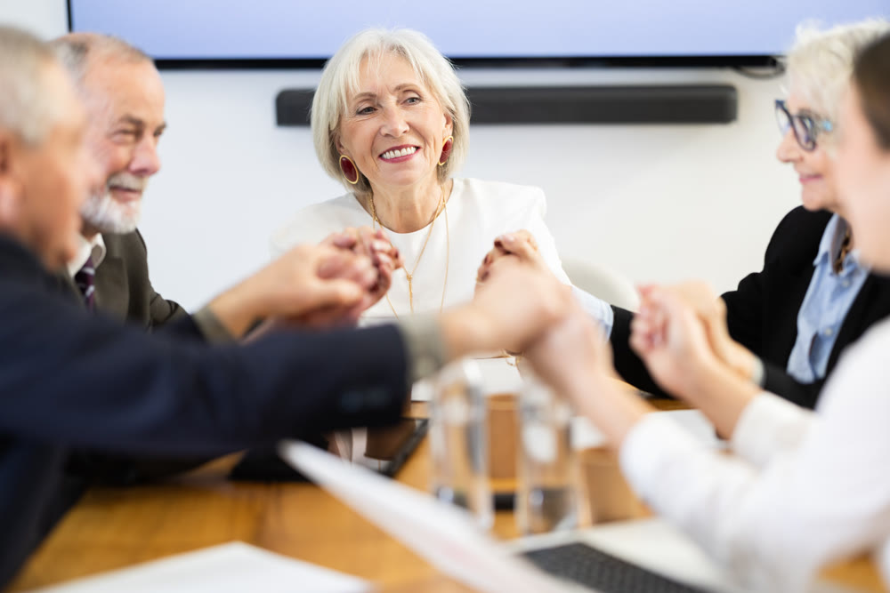 Team of seniors hold hands before starting work
