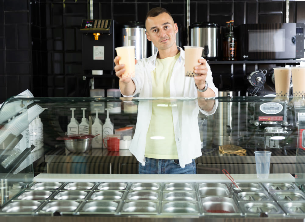 Happy man with two glasses of bubble tea in the grocery department of supermarket