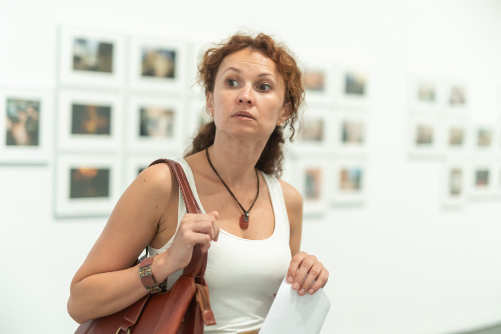 Middle-aged woman looking at pictures on wall in museum