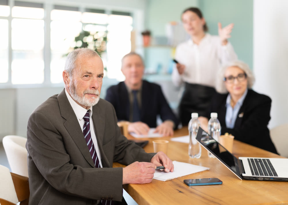 Elderly man in group watches presentation given by young secretary