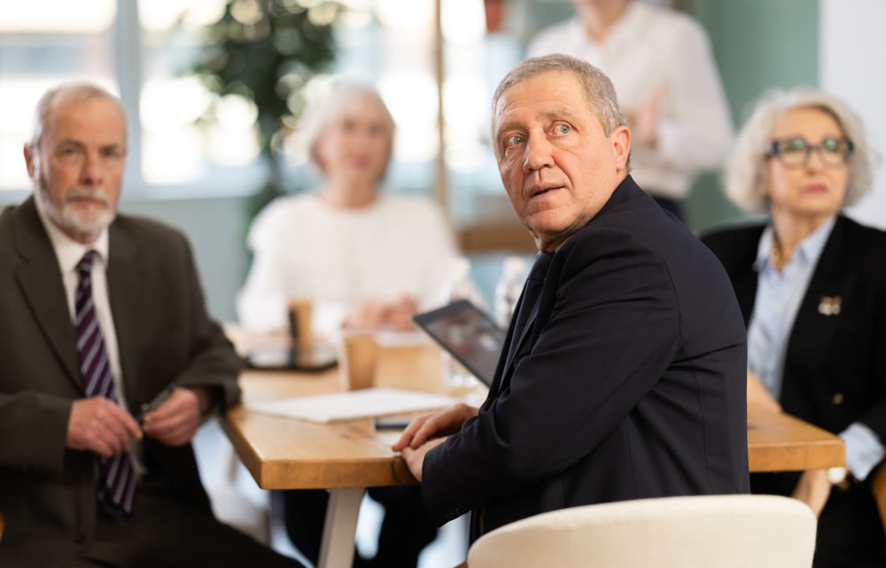 Elderly man in group watches presentation given by young secretary