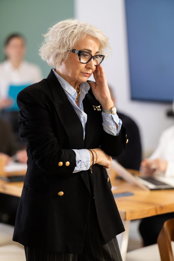 Confused elderly woman in office during meeting