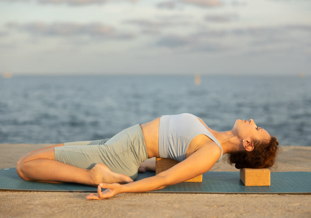 Yoga practice on embankment, female athlete fulfil carry out frog asana with blocks