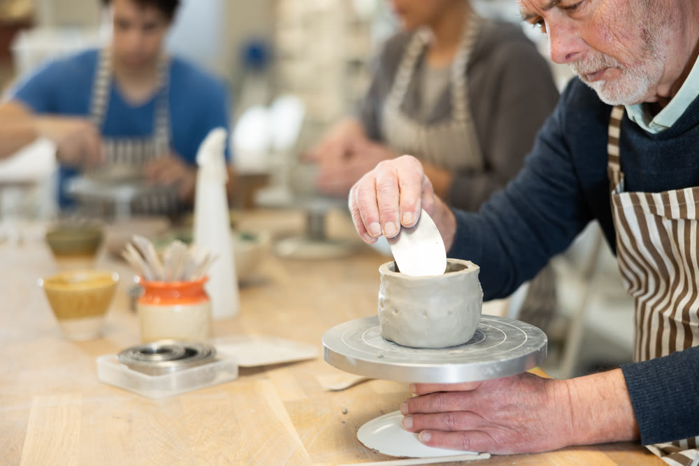 Eldery man sculpts ceramic piece in workshop