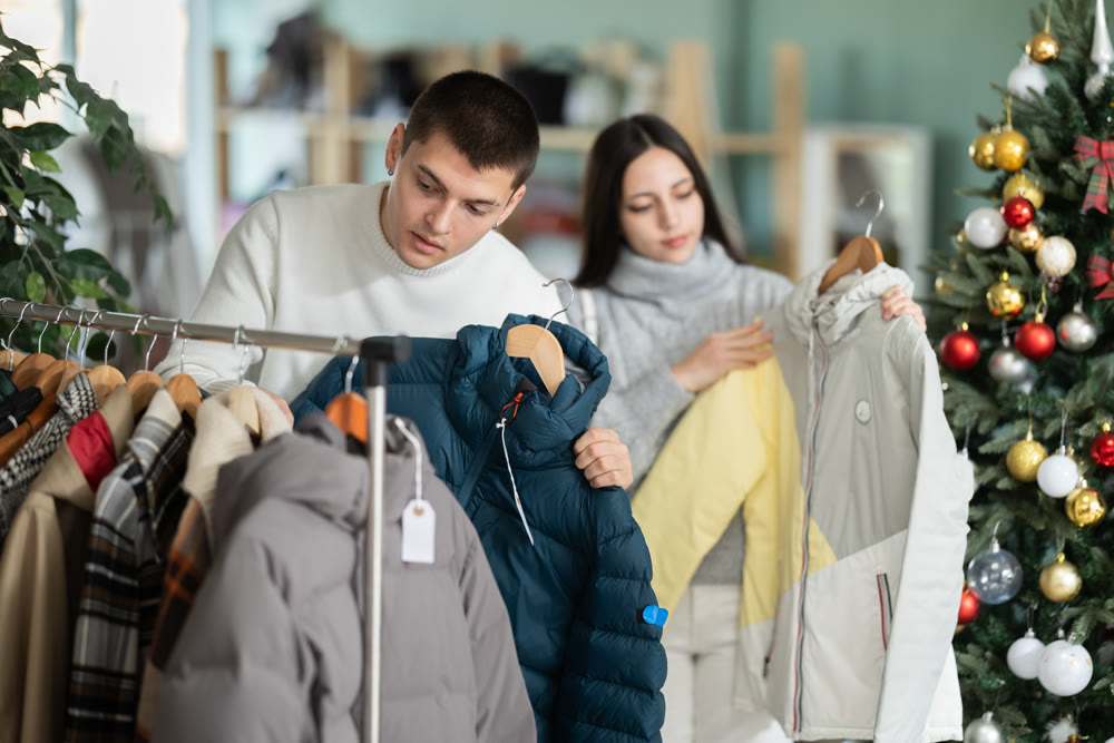 Young couple choosing coat or jacket in clothing store