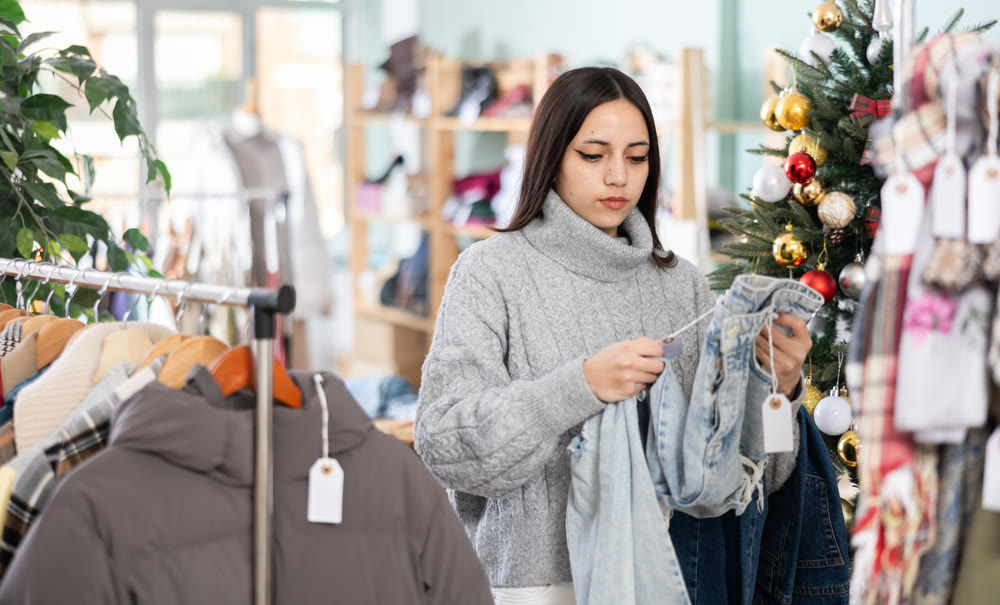 Girl shopper chooses jeans in clothing store before Christmas